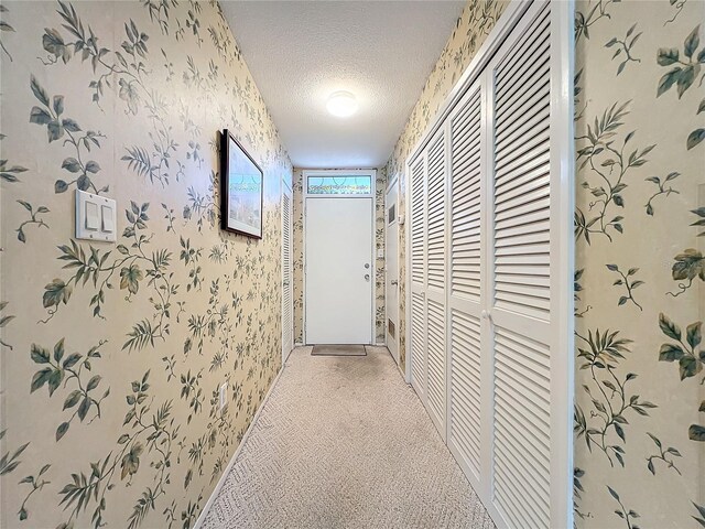 hallway featuring carpet flooring and a textured ceiling