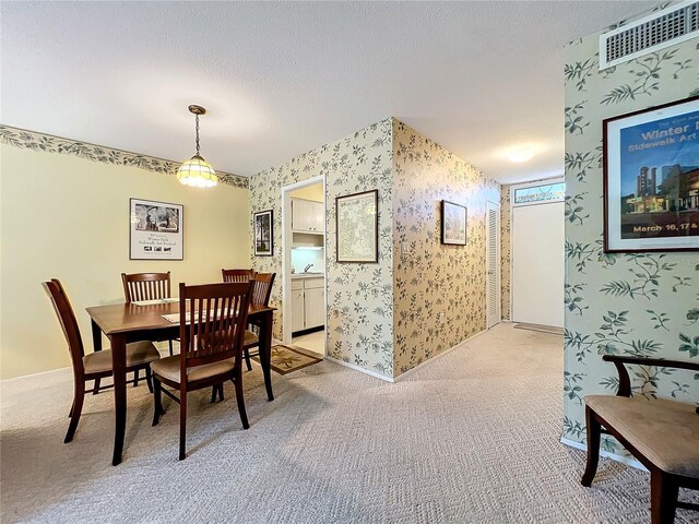 dining room with light colored carpet, sink, and a textured ceiling