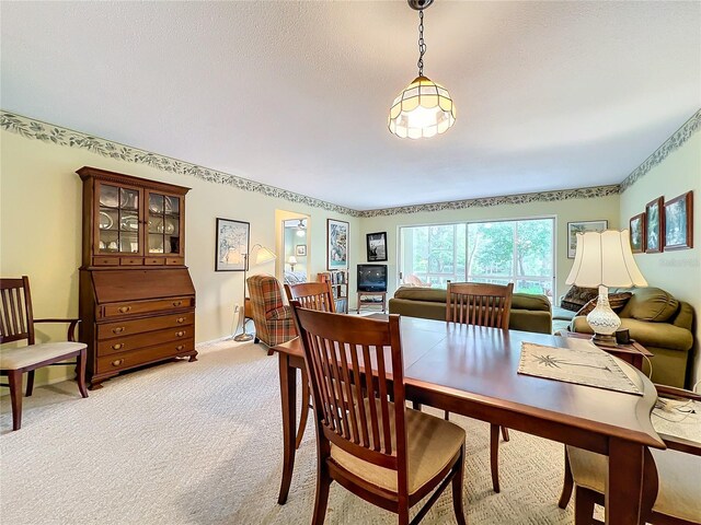 dining space featuring light colored carpet and a textured ceiling