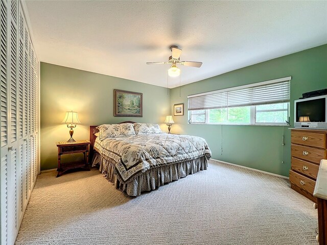 bedroom featuring light carpet, a textured ceiling, and ceiling fan