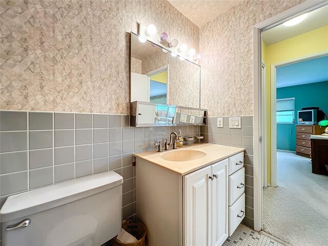 bathroom featuring vanity, tile walls, and toilet