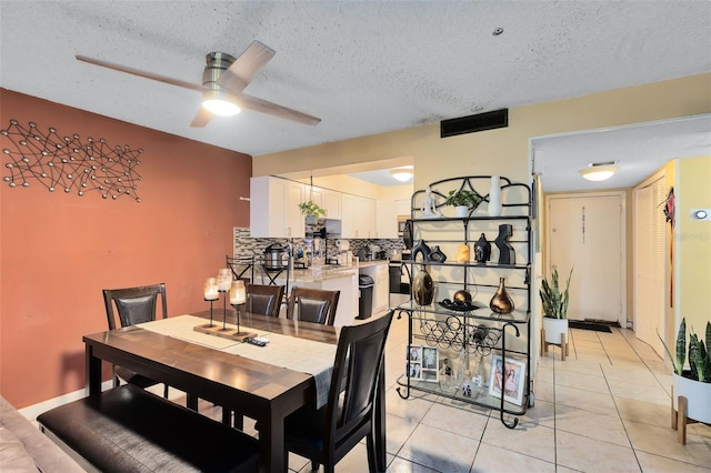 tiled dining area with a textured ceiling and ceiling fan