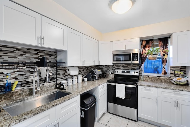 kitchen with white cabinetry, stainless steel appliances, light stone countertops, and tasteful backsplash