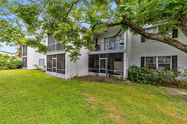 back of property featuring a balcony, a sunroom, and a yard