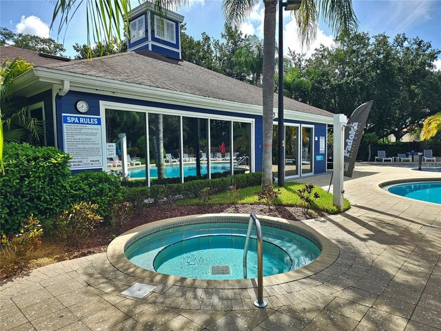 view of pool with a community hot tub and a patio area