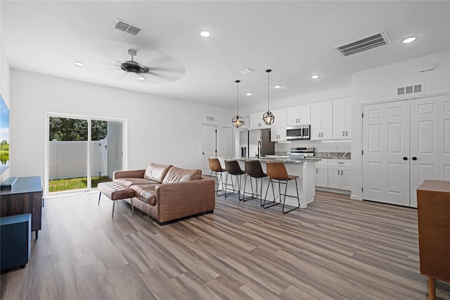 living room featuring light wood-type flooring and ceiling fan