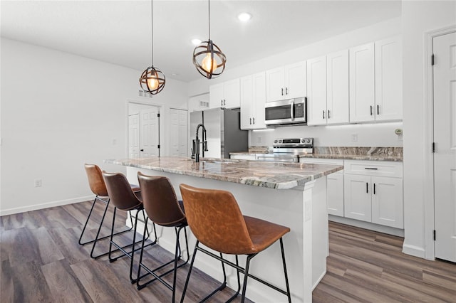 kitchen with dark wood-type flooring, white cabinetry, a kitchen island with sink, and stainless steel appliances