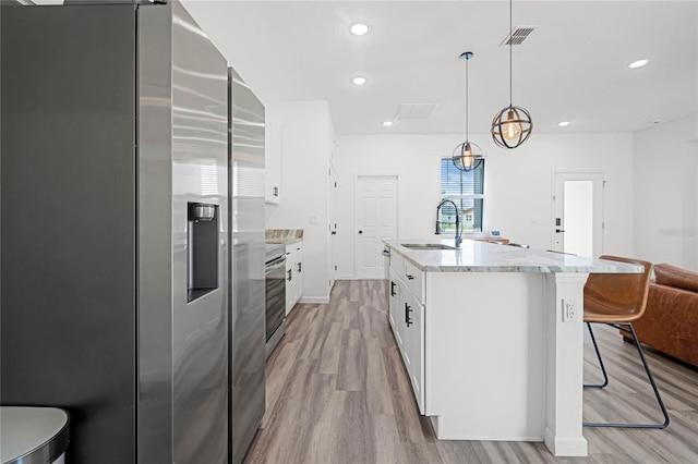 kitchen featuring white cabinetry, light wood-type flooring, high end fridge, hanging light fixtures, and sink