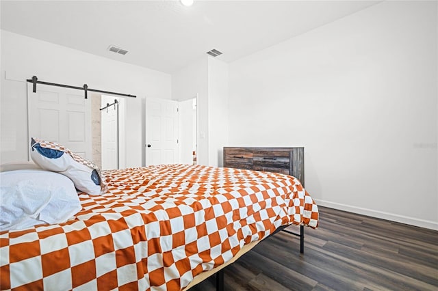 bedroom with wood-type flooring and a barn door