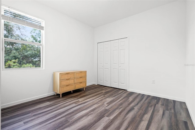 unfurnished bedroom with dark hardwood / wood-style flooring and a closet