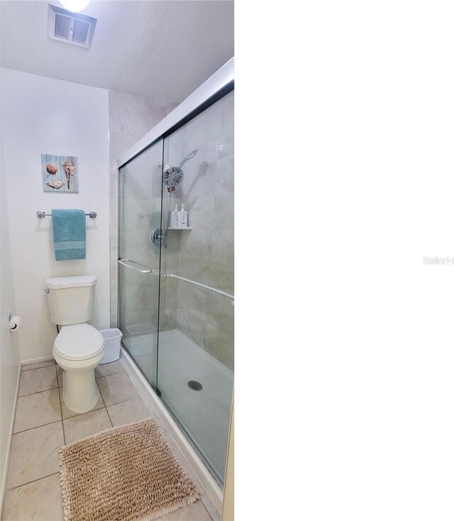 bathroom with tile patterned floors, walk in shower, and toilet