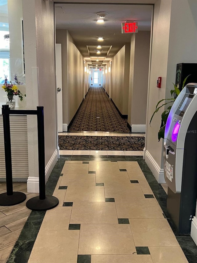 hallway featuring dark tile patterned flooring and a healthy amount of sunlight