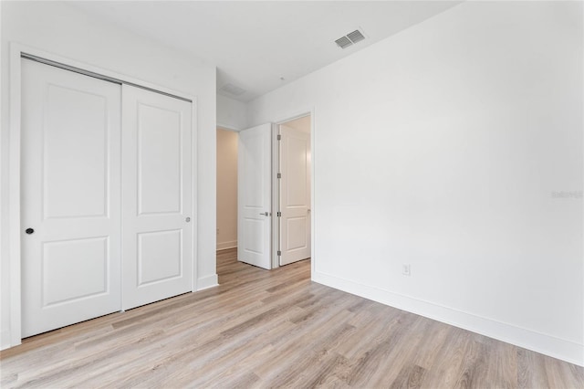 unfurnished bedroom with light hardwood / wood-style flooring and a closet