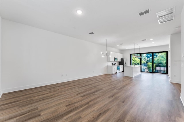 unfurnished living room featuring dark wood-type flooring and a chandelier