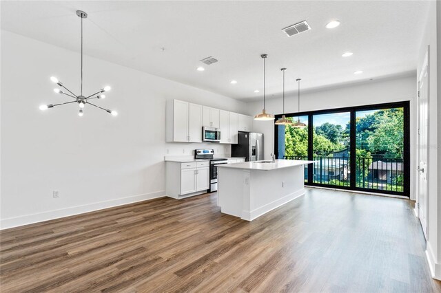 kitchen with stainless steel appliances, an island with sink, white cabinetry, hardwood / wood-style flooring, and decorative light fixtures