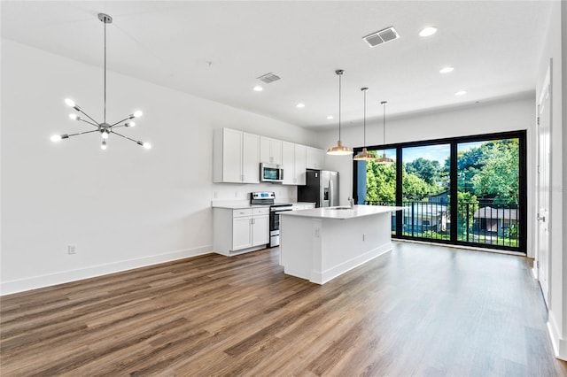 kitchen with hardwood / wood-style floors, stainless steel appliances, an island with sink, white cabinets, and decorative light fixtures