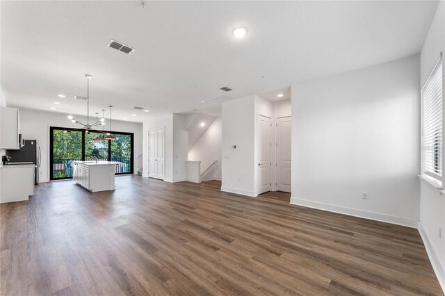 unfurnished living room featuring dark hardwood / wood-style flooring and a chandelier