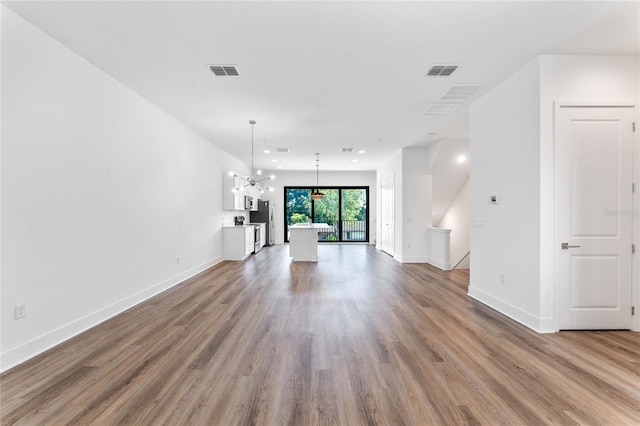 unfurnished living room with hardwood / wood-style flooring and a notable chandelier