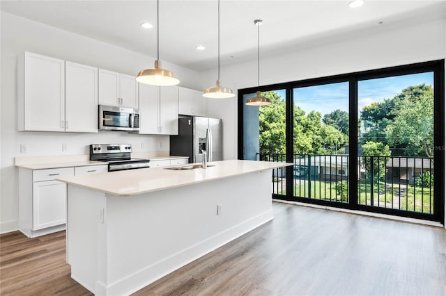 kitchen with pendant lighting, an island with sink, white cabinets, and appliances with stainless steel finishes