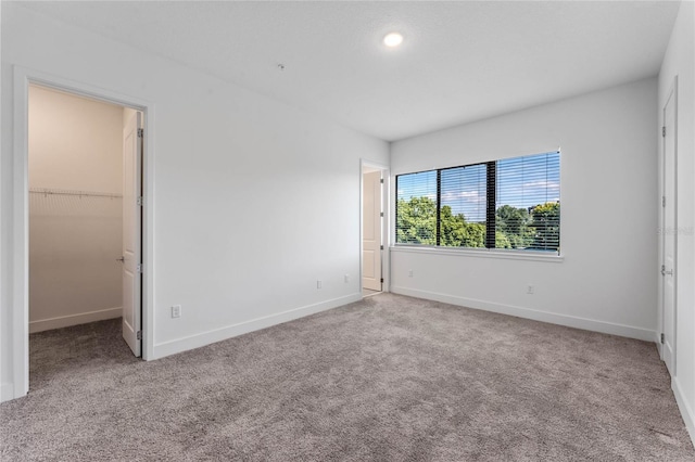 unfurnished bedroom with a spacious closet and light carpet