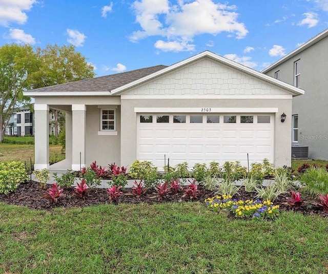 view of front of property with a front yard, a garage, and central AC