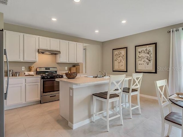 kitchen featuring white cabinetry, an island with sink, a breakfast bar area, stainless steel gas stove, and sink