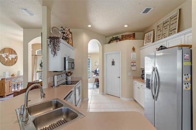 404 Hightower Dr, Debary, FL 32713 - kitchen with stainless steel appliances, arched walkways, a sink, white cabinets, and a textured ceiling