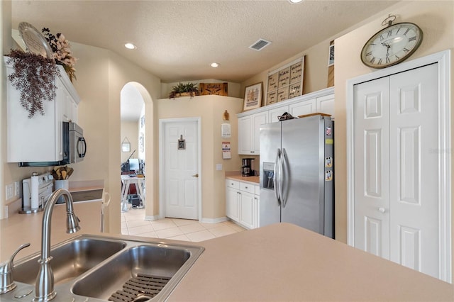 404 Hightower Dr, Debary, FL 32713 - kitchen with stainless steel appliances, a sink, arched walkways, white cabinetry, and light tile patterned floors