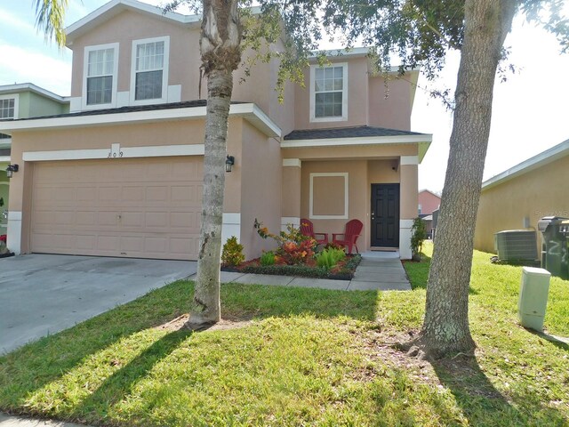 front of property featuring a garage, central AC, and a front yard