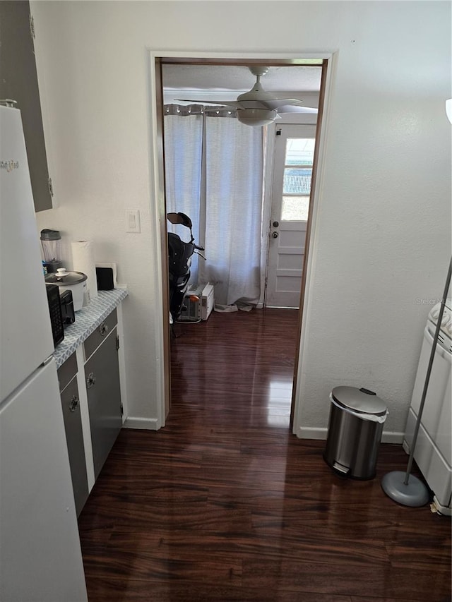 kitchen featuring light stone countertops, white fridge, and dark wood-type flooring