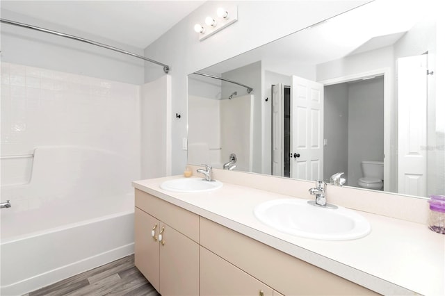 full bathroom with double vanity, hardwood / wood-style flooring, toilet, and shower / tub combination