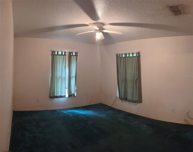 spare room featuring carpet floors, a textured ceiling, and ceiling fan