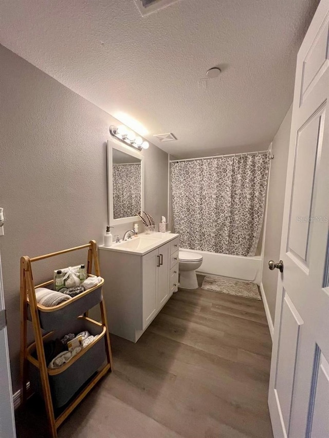 bathroom with toilet, hardwood / wood-style floors, vanity, and a textured ceiling