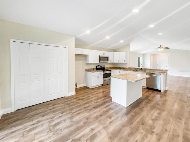 kitchen featuring a center island, vaulted ceiling, appliances with stainless steel finishes, kitchen peninsula, and white cabinets