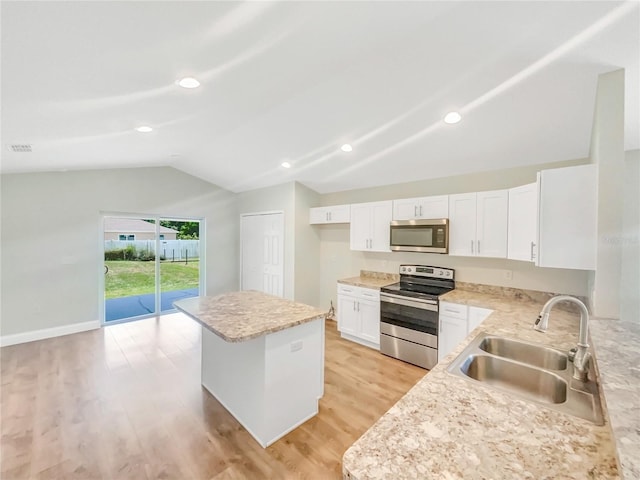 kitchen with sink, white cabinetry, vaulted ceiling, light hardwood / wood-style flooring, and appliances with stainless steel finishes