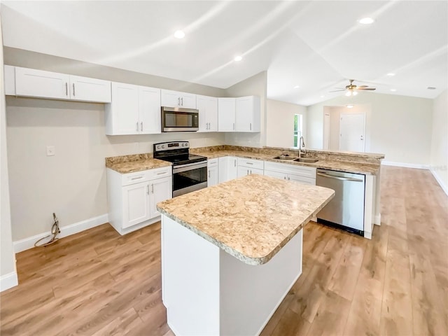 kitchen with appliances with stainless steel finishes, sink, white cabinets, kitchen peninsula, and light wood-type flooring