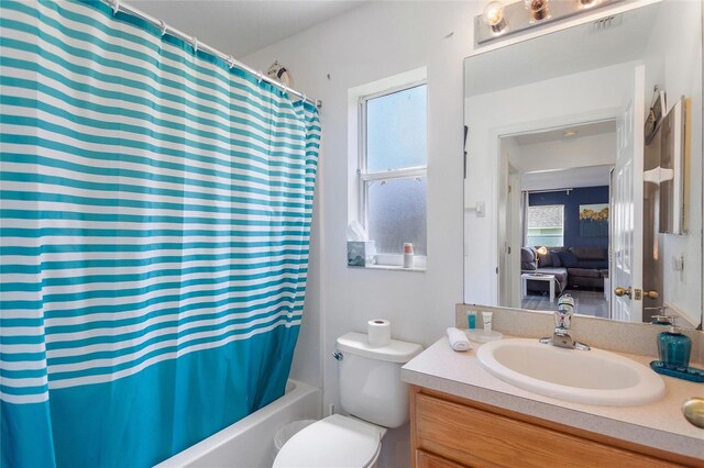 full bathroom featuring shower / bathtub combination with curtain, toilet, a wealth of natural light, and vanity