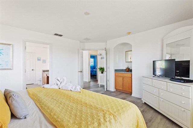 bedroom with ensuite bathroom and light wood-type flooring