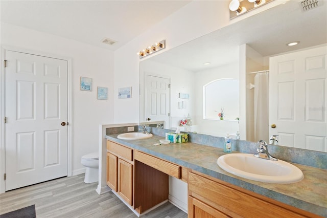 bathroom featuring toilet, hardwood / wood-style flooring, and double vanity