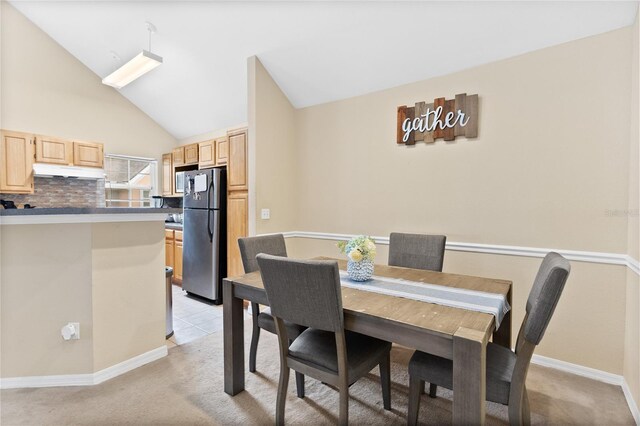 carpeted dining space featuring high vaulted ceiling