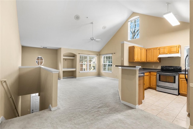 kitchen featuring under cabinet range hood, light colored carpet, stainless steel range with electric cooktop, a wealth of natural light, and dark countertops