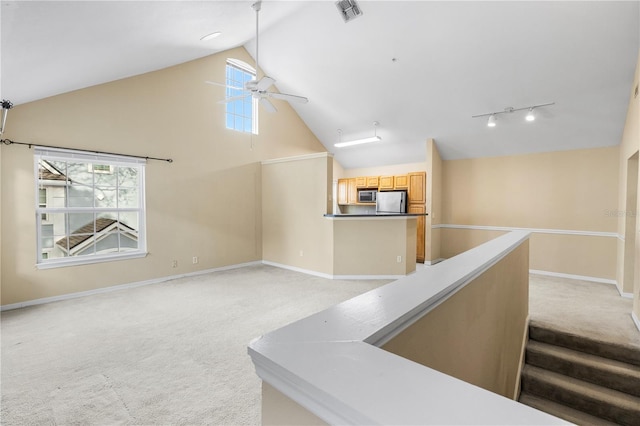 interior space with visible vents, light carpet, track lighting, high vaulted ceiling, and baseboards