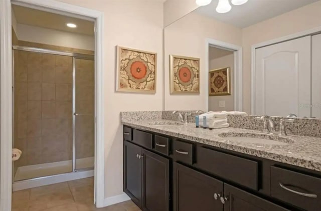 full bath with a shower stall, double vanity, a sink, and tile patterned floors