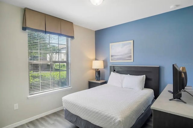 bedroom featuring light wood finished floors and baseboards