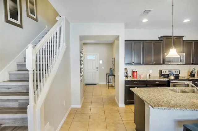 kitchen featuring light stone counters, decorative backsplash, appliances with stainless steel finishes, a sink, and dark brown cabinets