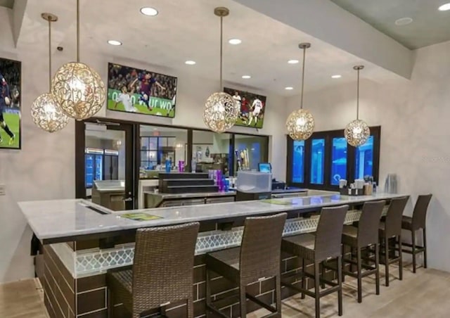 bar with light wood-type flooring, hanging light fixtures, and recessed lighting