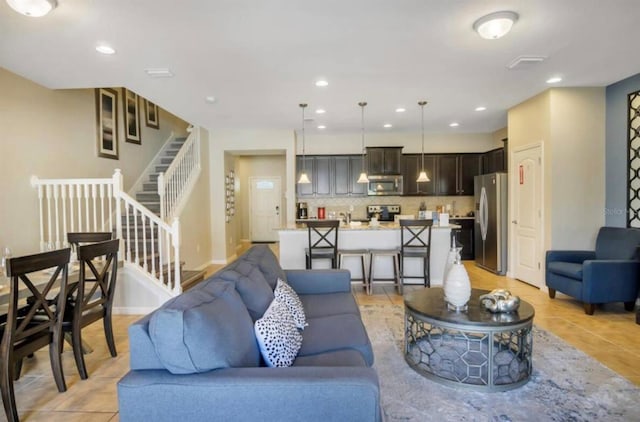 living area featuring light tile patterned floors, baseboards, visible vents, recessed lighting, and stairs