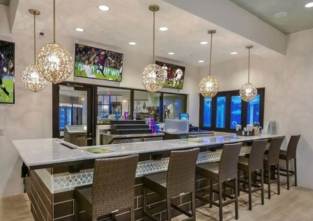 bar featuring light wood finished floors, decorative light fixtures, and recessed lighting