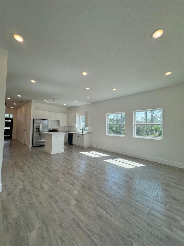 unfurnished living room with light wood finished floors, baseboards, and recessed lighting