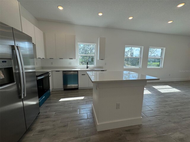 kitchen with appliances with stainless steel finishes, light countertops, white cabinetry, a sink, and recessed lighting